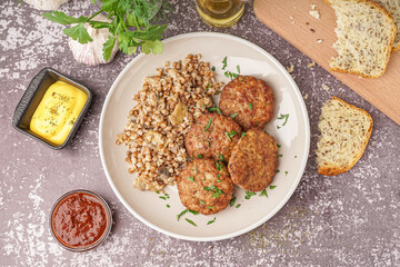Cutlets with buckwheat, mushrooms and parsley on grey grunge table in kitchen
