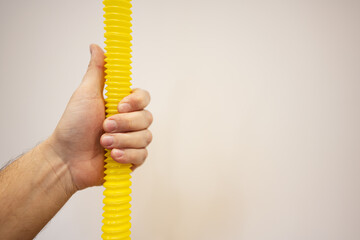 Close-up of male hand holding yellow hose against white background with copy space