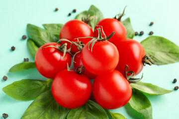 Composition with ripe cherry tomatoes, basil leaves and peppercorn on turquoise background, closeup