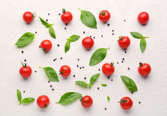 Composition with ripe cherry tomatoes, basil leaves and peppercorn on light background