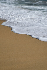 Close up of a beautiful sandy beach and white foamy waves in Ios Greece