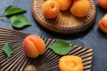 Boards with fresh apricots and leaves on black background