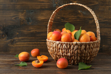 Fototapeta na wymiar Wicker basket with fresh apricots on wooden background