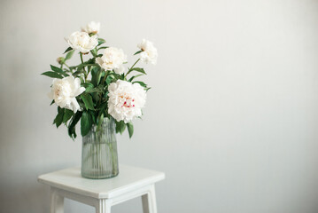 bouquet of white flowers peonies in a vase on the chair