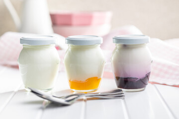White and fruity yogurt in jar on white table.