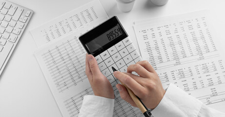 Obraz premium Accountant using calculator on desk office on white background with financial statement. Top view