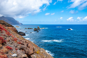 Die beeindruckende Steilküste von Benijo. Hohe Klippen und Felsen prägen die Landschaft. Panorama mit weitem Blick aufs Meer. Der Himmel ist von Wolken durchzogen. Playa de Benijo am Fuße der Klippen