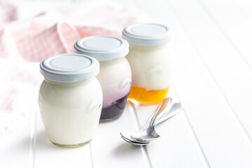 White and fruity yogurt in jar on white table.