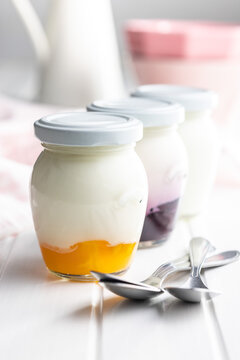 White and fruity yogurt in jar on white table.