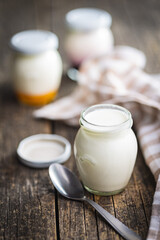 White yogurt in jar on wooden table.