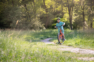 Naklejka premium a child wearing a helmet on an orange bike ride in a city park. A sunny summer day. copy space. children bike helmet 