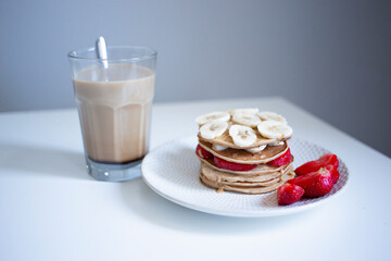 stack of pancakes on a plate with fruits and coffee