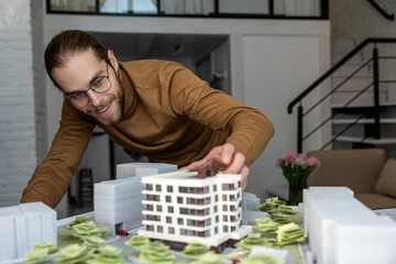 Man architect working in office on creation of new residential complex designing layout of buildings