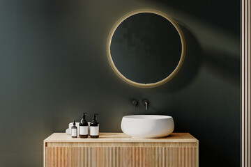 Close up of sink with oval mirror standing in on green wall , wooden vanity with black faucet in...