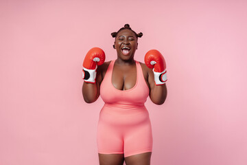 Portrait of emotional African American woman, professional boxer wearing red boxing gloves...