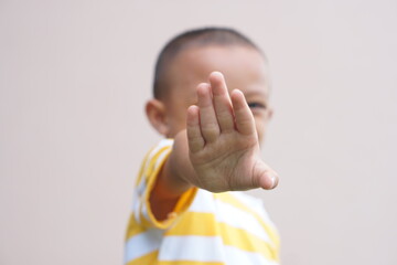 The boy raised his hand in front of himself to defend himself.