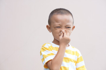 A boy covering his nose with his hands from getting a bad smell