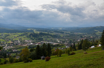 Scenic view of Vorokhta village in a valley surrounded mountains against cloudy sky. Carpathians, Ukraine
