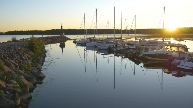 Panoramic view of yachts sunset time with golden light falling on trees with yachts docked in bay video background.