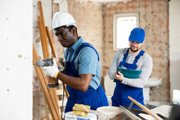 Head of construction checks how the builder works with a puncher