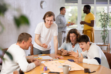 Group of active men play board games during a friendly meeting