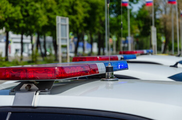 Police car flashing light. In the background, the flags of Russia are out of focus.