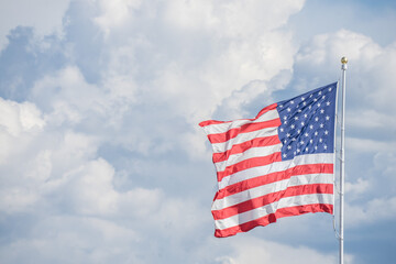 Obraz premium American Flag flying against blue skies and clouds
