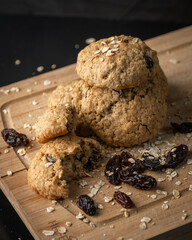 Oatmeal, cinnamon and raisins cookies on a wooden board with a dark background