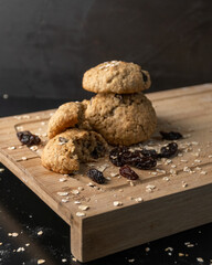 Oatmeal, cinnamon and raisins cookies on a wooden board with a dark background