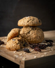 Oatmeal, cinnamon and raisins cookies on a wooden board with a dark background
