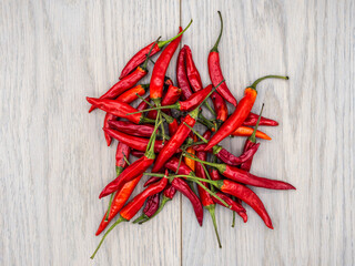 Red and orange chili fruits on a wooden background seen from above.