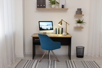 Cozy workspace with computer on wooden desk and comfortable chair at home