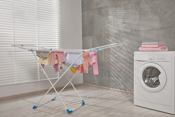 Clean laundry hanging on drying rack indoors