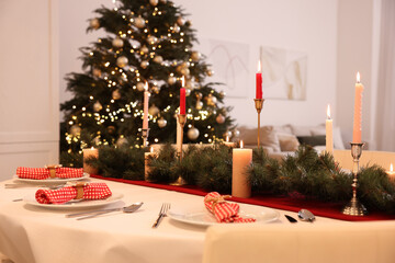 Festive table setting and beautiful Christmas decor in room. Interior design