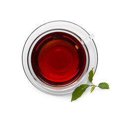 Glass cup of hot aromatic tea and green leaves on white background, top view