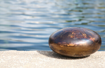 Steel tongue drum near sea, space for text. Percussion musical instrument