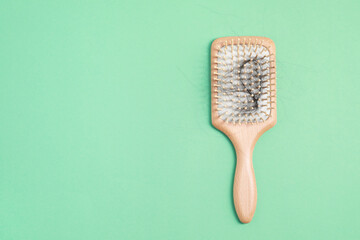 Wooden brush with lost hair on green background, top view. Space for text