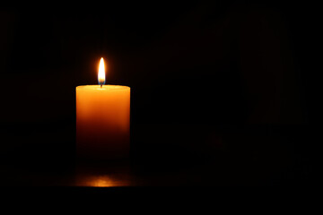 One burning candle on black background, space for text