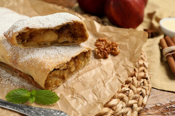 Delicious apple strudel with walnuts and powdered sugar on table, closeup. Space for text