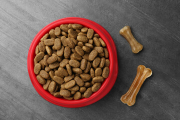 Dry dog food and treats (chew bones) on textured background, flat lay