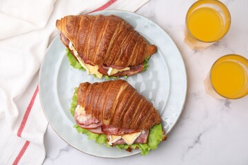 Tasty croissants with brie cheese, ham and bacon on white marble table, flat lay