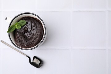 Tasty chocolate mug pie and spoon on white table, top view with space for text. Microwave cake recipe
