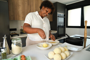 Fototapeta na wymiar Young cuban woman breading mashed potatoes balls to prepare cuban style stuffed potatoes.