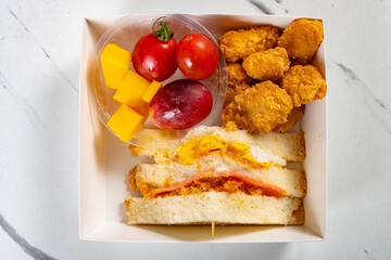 top view snack of sandwich and deep fried diced chicken and grape and mangoes and sweet potatoes