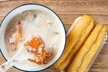 top view seafood porridge with crabs and shrimps and white shells and deep-fried dough sticks horizontal composition