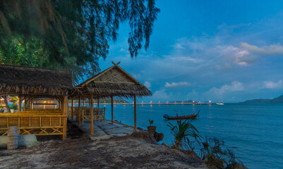 Sunset over Rawai Beach in Phuket island Thailand. Lovely turquoise blue waters, lush green mountains colourful skies and beautiful views the pier and long tail boats. Sky is taken seperate from Body 