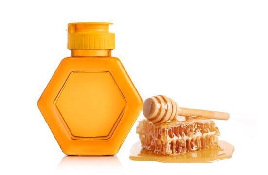 Bottle of honey with wooden dipper and honey comb isolated on white background.