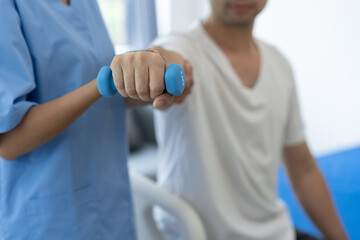 Physiotherapist giving therapy exercise with dumbbell equipment on male patient athlete arm and shoulder, physiotherapy concept, health insurance.