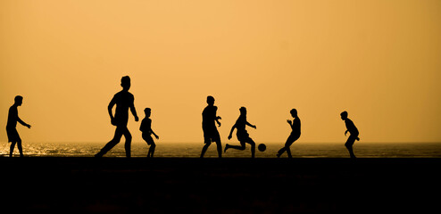Fototapeta na wymiar silhouettes of boys playing football