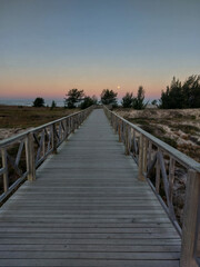 Fototapeta premium Wooden walkway leading to the beach at sunset in summer
